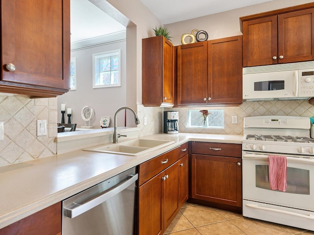 kitchen featuring tasteful backsplash, sink, light tile patterned floors, and white appliances