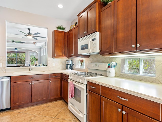 kitchen featuring sink, ceiling fan, light tile patterned floors, white appliances, and tasteful backsplash