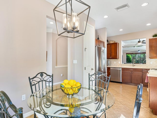 dining room featuring sink, crown molding, light tile patterned floors, and ceiling fan with notable chandelier