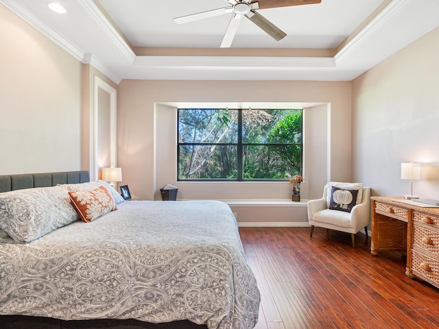 bedroom with ornamental molding, dark wood-type flooring, a raised ceiling, and ceiling fan