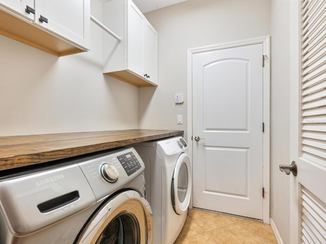 laundry area featuring light tile patterned flooring, washing machine and dryer, and cabinets