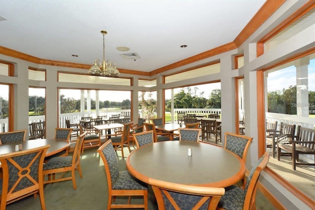 dining room featuring an inviting chandelier, ornamental molding, and carpet