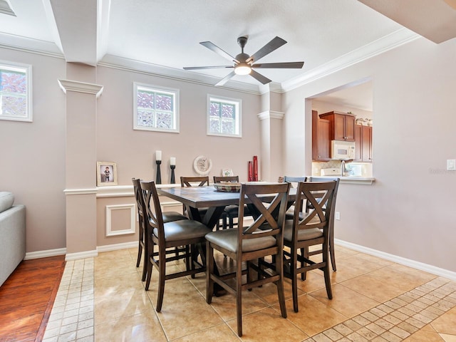 tiled dining area featuring crown molding, ceiling fan, and decorative columns