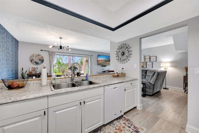 kitchen with an inviting chandelier, dishwasher, sink, white cabinetry, and light hardwood / wood-style flooring