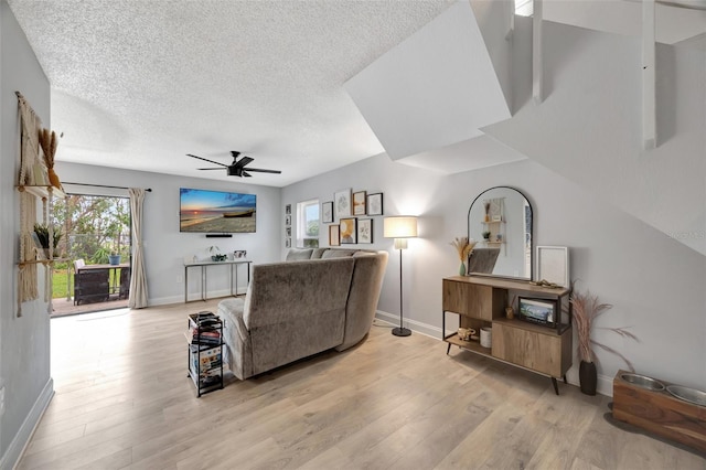 living room featuring a textured ceiling, light wood-type flooring, and ceiling fan