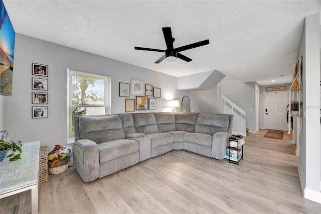 living room with light wood-type flooring, a textured ceiling, and ceiling fan