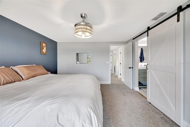 carpeted bedroom with a barn door and a textured ceiling