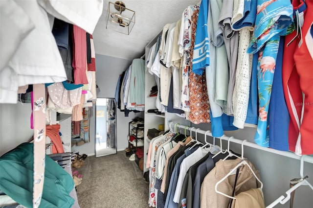 walk in closet featuring dark carpet