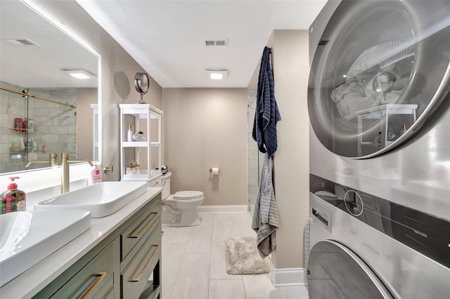 bathroom featuring stacked washing maching and dryer, an enclosed shower, vanity, and toilet