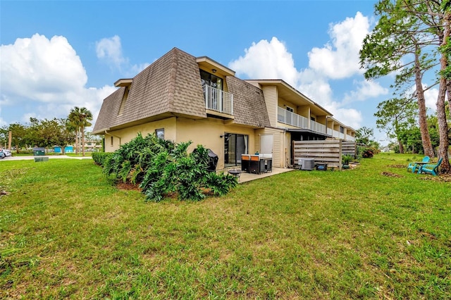 back of house featuring a lawn, a balcony, and cooling unit