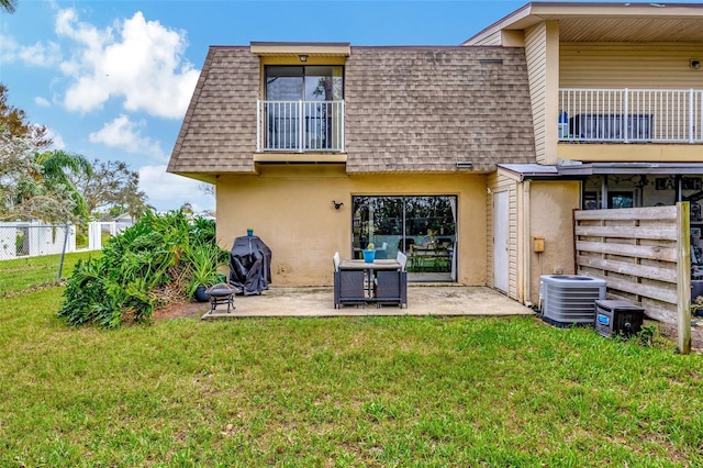 rear view of house with a lawn, a balcony, cooling unit, and a patio area