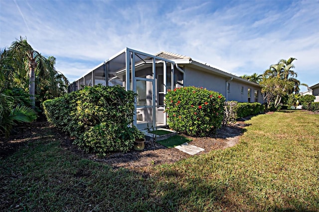 view of side of home with a lawn and a lanai