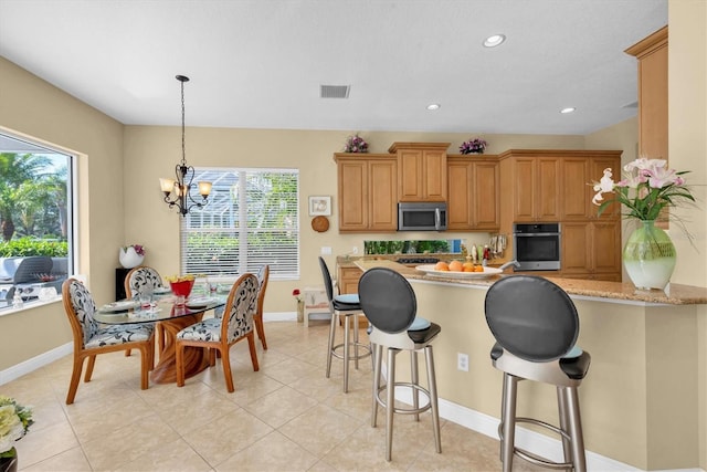 kitchen featuring stainless steel appliances, light stone counters, a notable chandelier, kitchen peninsula, and decorative light fixtures