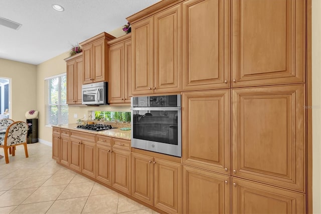 kitchen featuring light stone countertops, light tile patterned floors, and stainless steel appliances