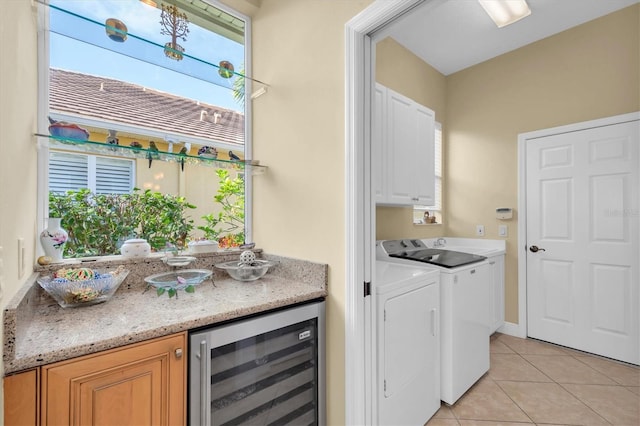 washroom featuring independent washer and dryer, cabinets, light tile patterned floors, and beverage cooler