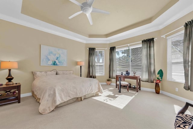 carpeted bedroom with ceiling fan, a tray ceiling, and multiple windows