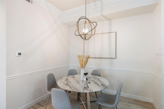 dining area with a chandelier, light hardwood / wood-style floors, and ornamental molding