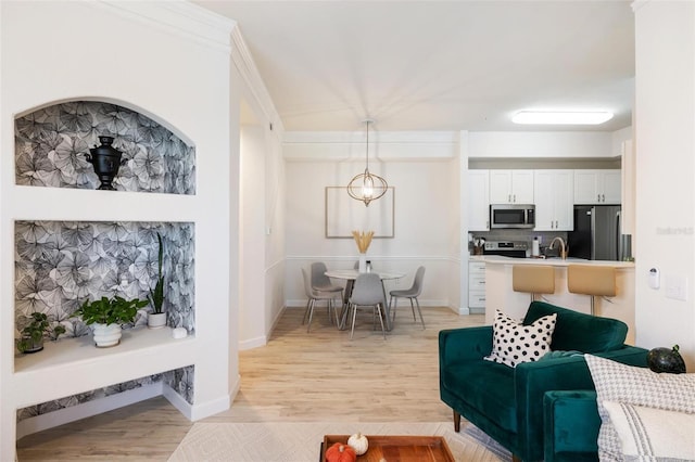 living room with light hardwood / wood-style flooring, ornamental molding, and sink