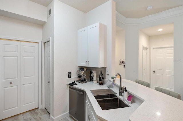 kitchen with light stone countertops, light wood-type flooring, stainless steel dishwasher, sink, and white cabinetry