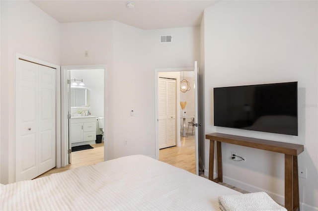 bedroom featuring light wood-type flooring and ensuite bath