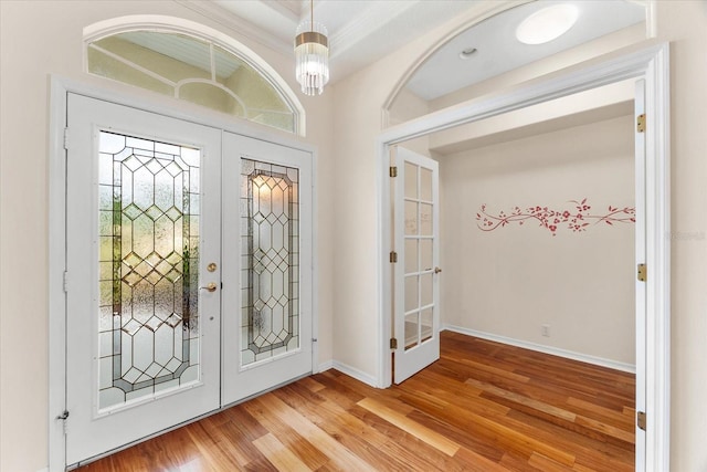 foyer entrance featuring an inviting chandelier, french doors, and light hardwood / wood-style flooring