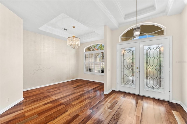 foyer entrance featuring a chandelier, french doors, a tray ceiling, and hardwood / wood-style flooring