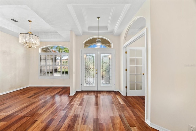 entryway with dark wood-type flooring, french doors, a tray ceiling, and a notable chandelier