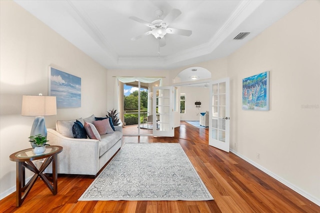 living room featuring a tray ceiling, dark hardwood / wood-style flooring, ceiling fan, and french doors