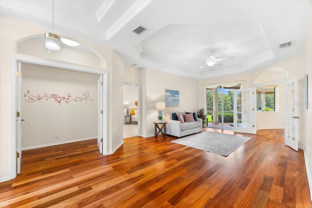 unfurnished living room with a tray ceiling, ceiling fan, french doors, and hardwood / wood-style floors