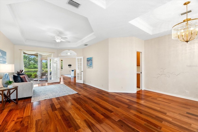 unfurnished living room featuring ceiling fan with notable chandelier, dark hardwood / wood-style flooring, french doors, and a tray ceiling