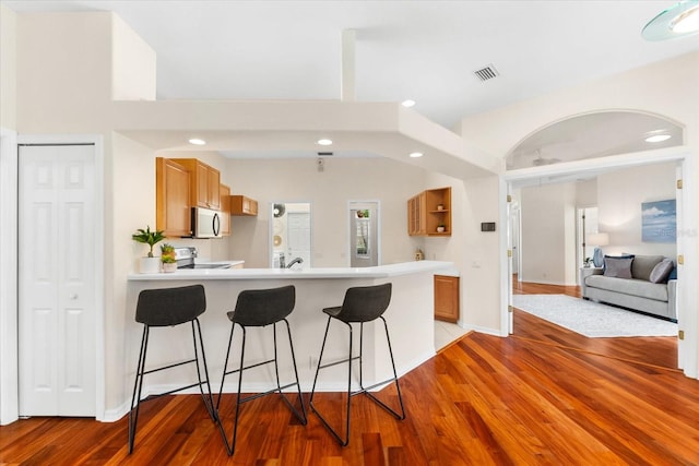 kitchen featuring a kitchen bar, kitchen peninsula, and white appliances