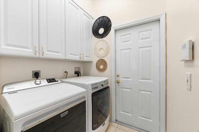 washroom featuring cabinets, light tile patterned floors, and washer and clothes dryer