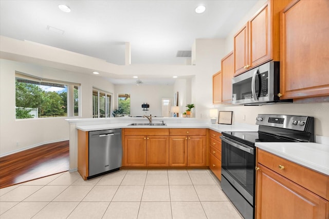 kitchen featuring kitchen peninsula, stainless steel appliances, ceiling fan, sink, and light tile patterned floors