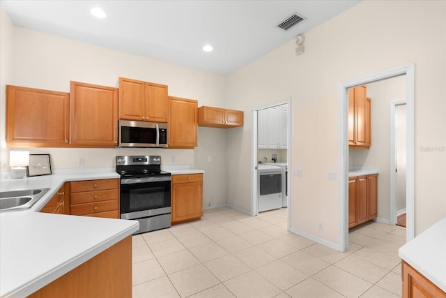 kitchen featuring appliances with stainless steel finishes, washer / clothes dryer, light tile patterned floors, and sink