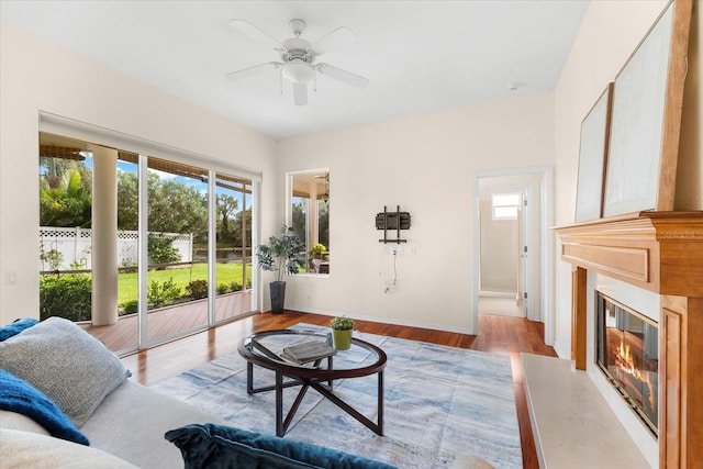 living room with ceiling fan, a premium fireplace, and light hardwood / wood-style flooring