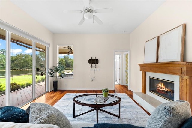 living room with ceiling fan, light hardwood / wood-style flooring, and a water view