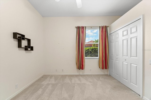 unfurnished bedroom with ceiling fan, light colored carpet, and a closet