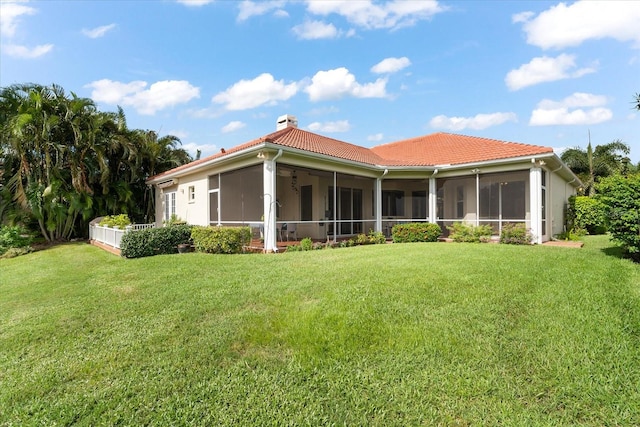 rear view of house featuring a sunroom and a yard