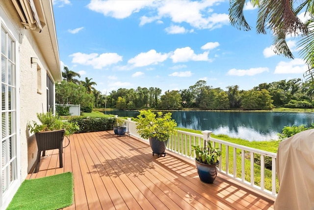 wooden terrace featuring a water view and a grill