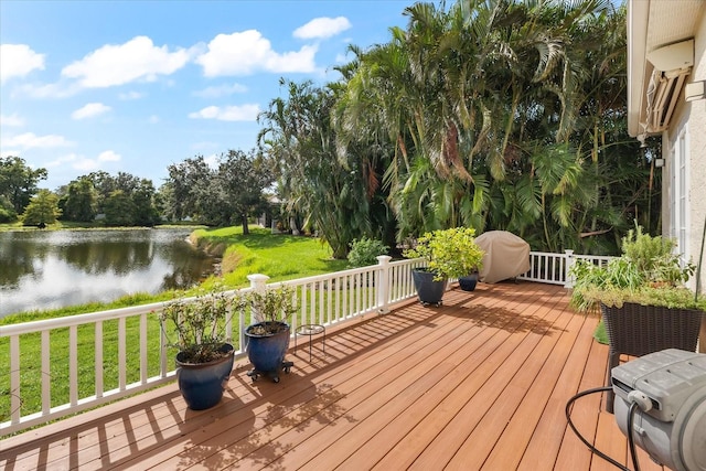 deck featuring a lawn, a grill, and a water view