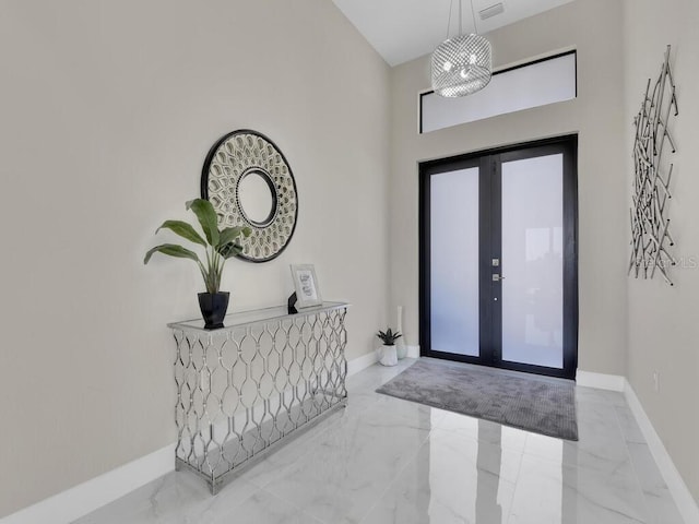 entryway with a towering ceiling, french doors, and a chandelier