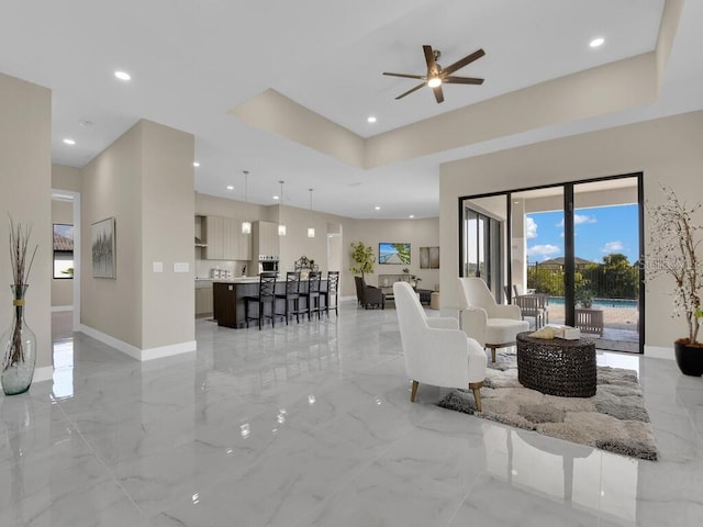 living room with a raised ceiling and ceiling fan