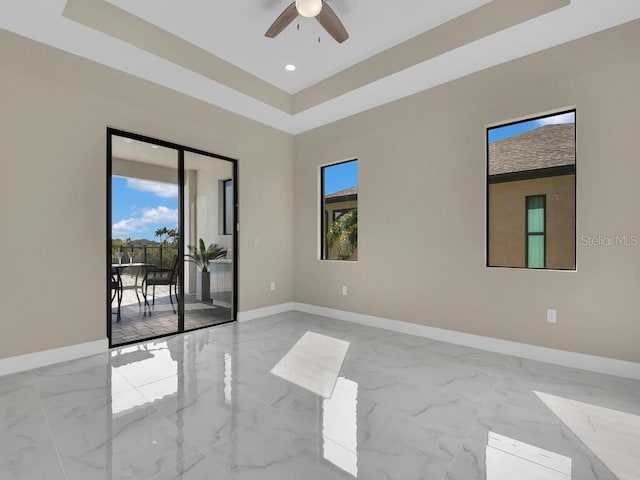 empty room featuring ceiling fan and a raised ceiling