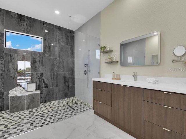 bathroom with a tile shower and vanity