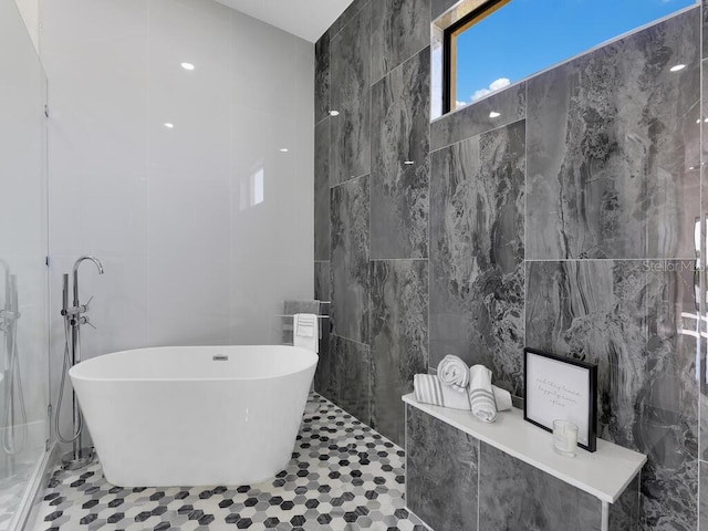 bathroom with tile patterned floors, a tub to relax in, and tile walls