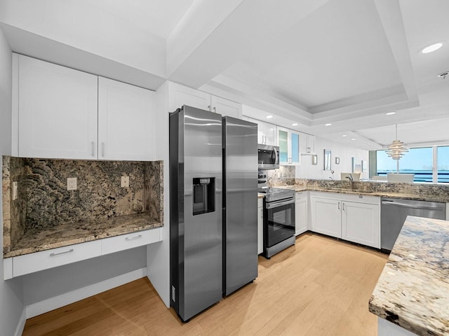 kitchen featuring a tray ceiling, white cabinetry, stainless steel appliances, and light wood-type flooring