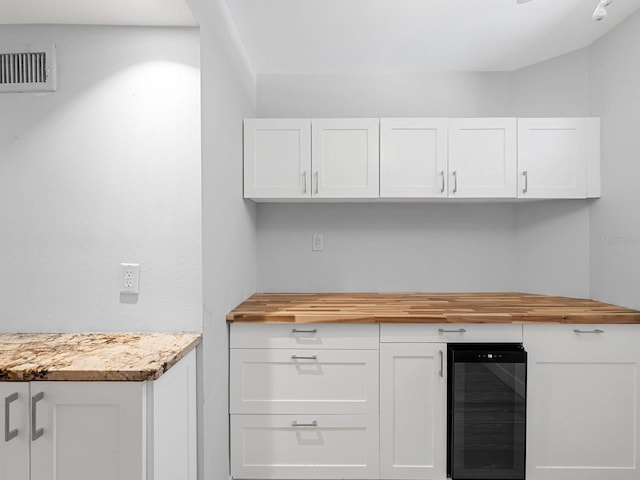 kitchen with white cabinetry, wooden counters, and beverage cooler