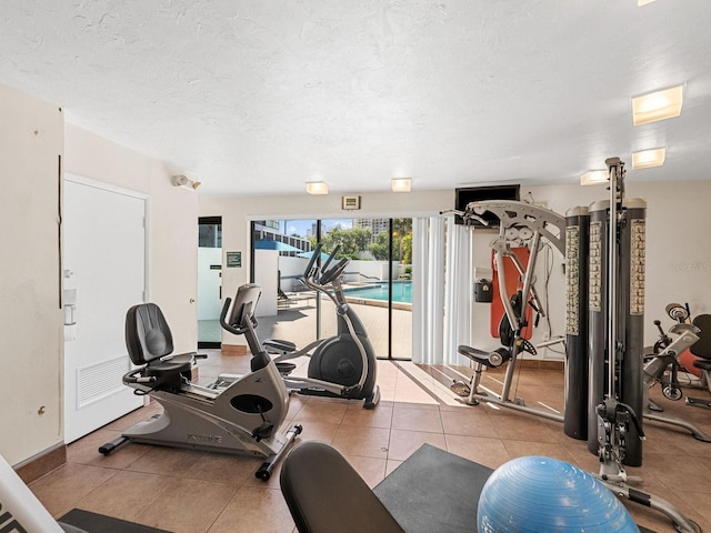 workout area with a textured ceiling and light tile patterned floors