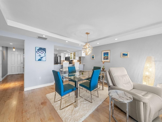 dining area featuring light wood-style floors, a raised ceiling, and recessed lighting