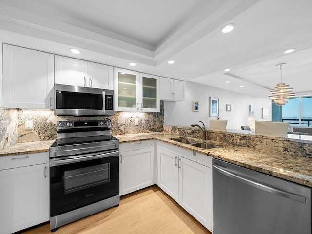 kitchen featuring stainless steel appliances, a tray ceiling, white cabinets, and glass insert cabinets